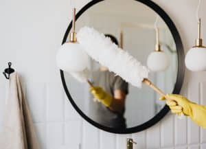 woman dusting mirror for house cleaning