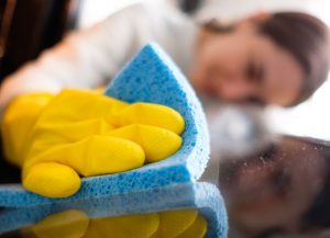 woman looking at counter while she wipes it clean with sponge