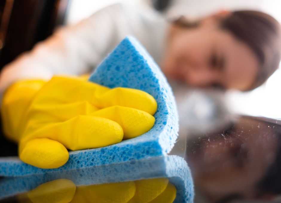woman looking at and washing off counter with sponge