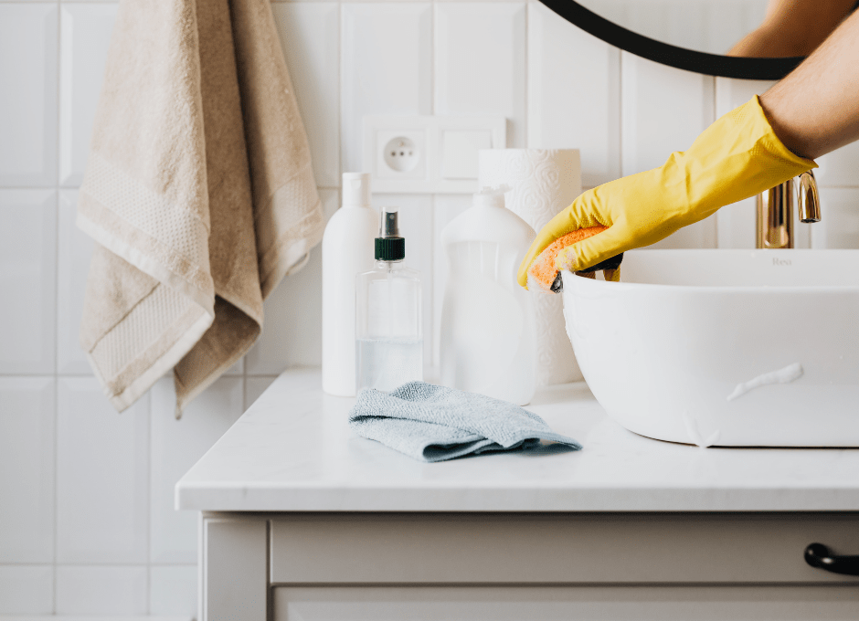 woman's hand on sink and cleaning products on counter