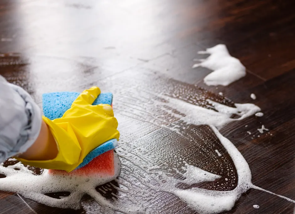 A woman wearing a yellow rubber glove scrubbing a floor